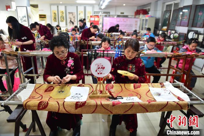 江西省級非遺豫章繡傳承人手把手指導(dǎo)小學(xué)生繡制2022年北京冬奧會吉祥物“冰墩墩”形象。 喻云亮 攝