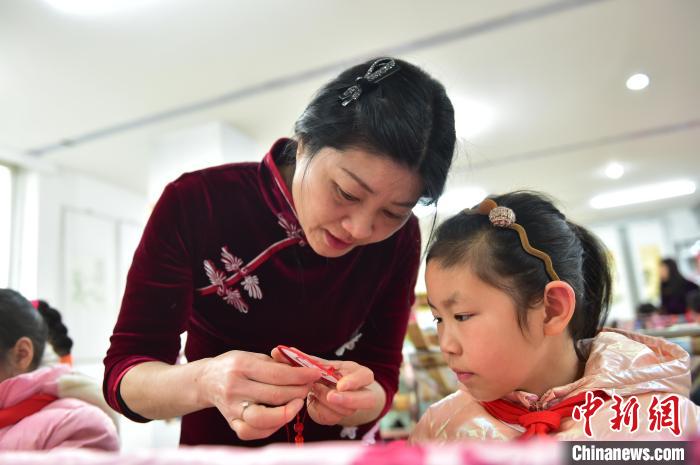 江西省級非遺豫章繡傳承人手把手指導(dǎo)小學(xué)生繡制2022年北京冬奧會吉祥物“冰墩墩”形象。 喻云亮 攝