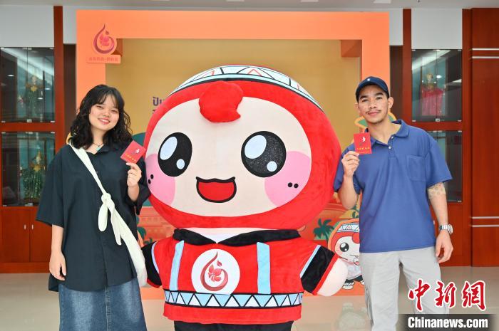 圖為泰國(guó)留學(xué)生手持獻(xiàn)血證與人偶合影?！∮峋?攝
