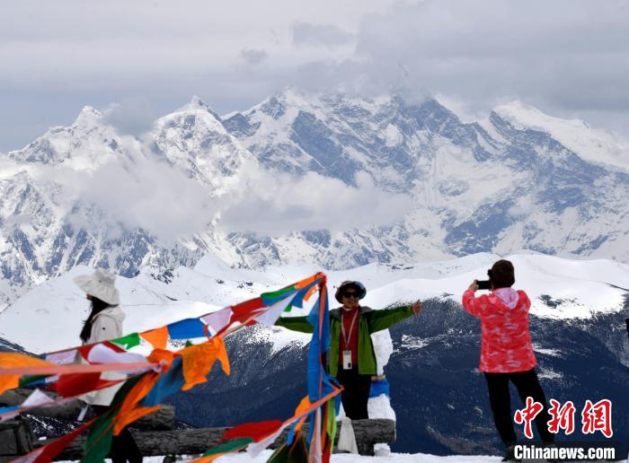 圖為5月14日,西藏林芝色季拉山觀景臺,游客與南迦巴瓦峰合影。 李林 攝