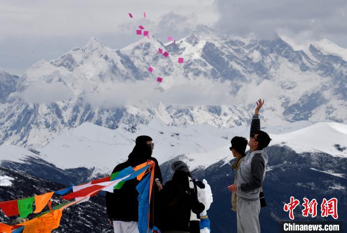 圖為5月14日,游客在西藏林芝色季拉山觀景臺拋灑“隆達”(風馬旗,藏族民眾的一種祈福方式)。 李林 攝