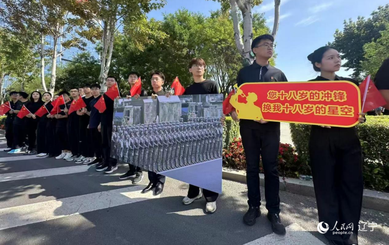 沈陽市人民廣場上，大學生們手持閱兵的圖片，告慰英烈。人民網(wǎng)記者 周頌雪攝