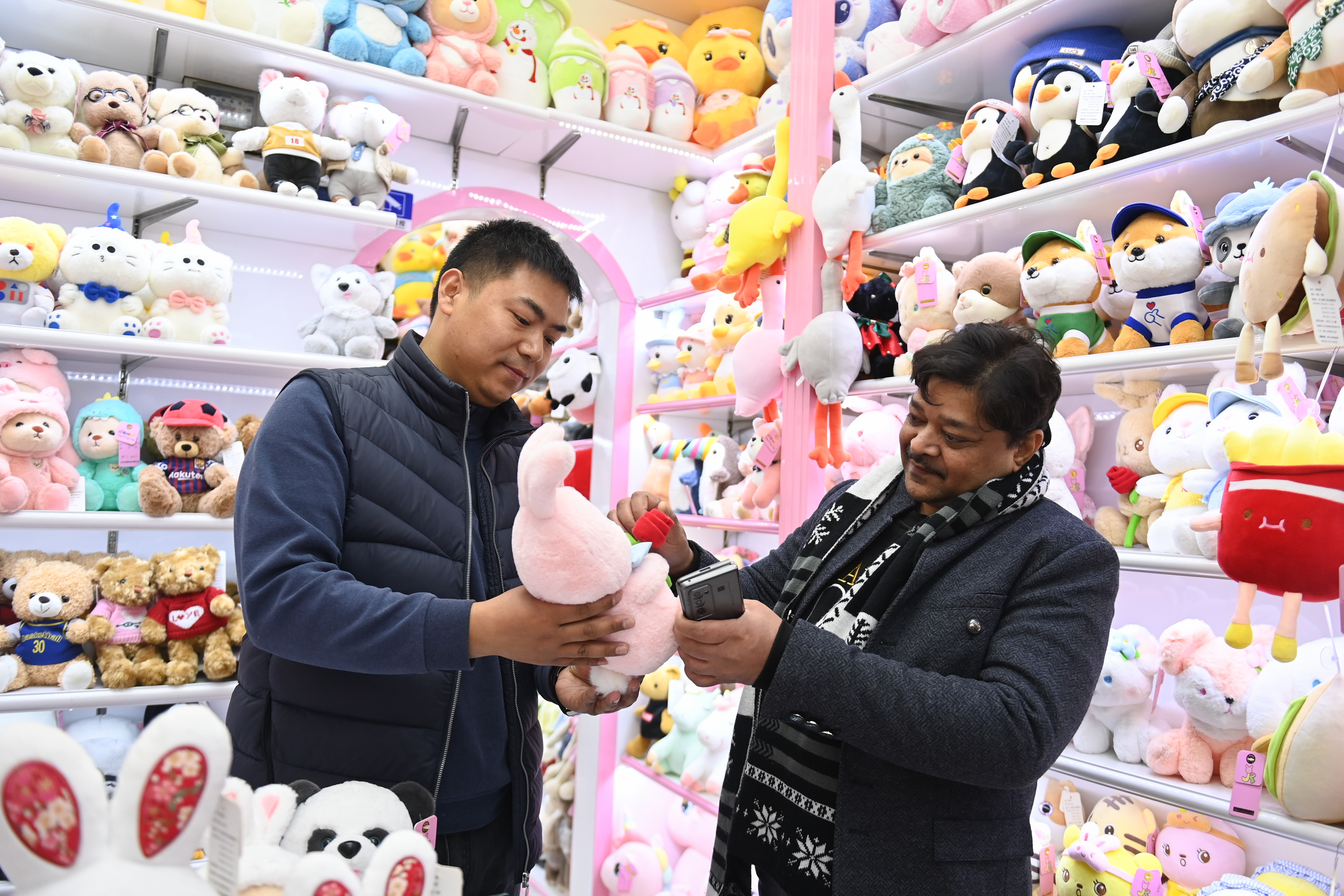 2023年2月2日，來自印度的客商（右）在義烏國際商貿城的一家玩具店鋪內選購。