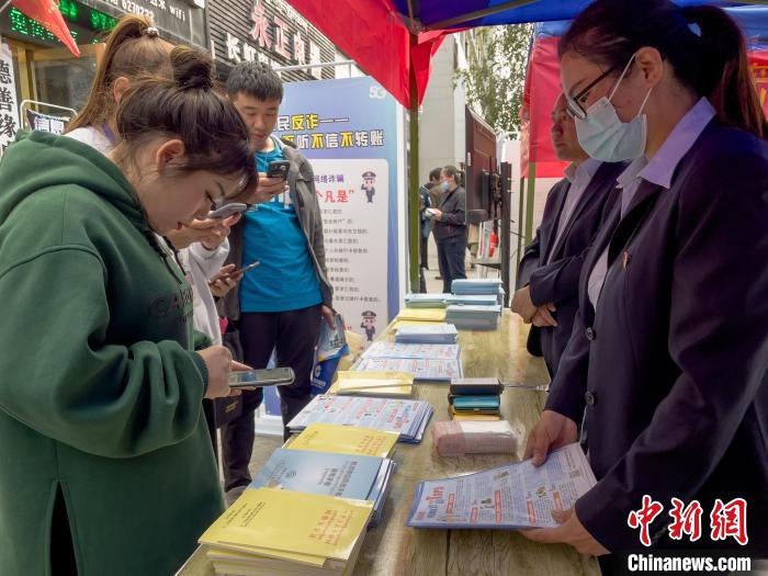 圖為工作人員正在向路過市民介紹國家反詐中心軟件的功能。　謝牧 攝