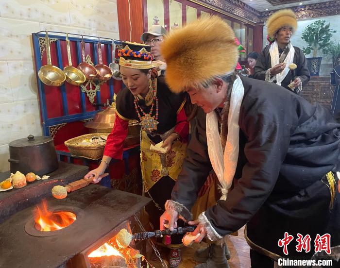 圖為人們在火上烤節日美食“結達”?！∪轿木?攝
