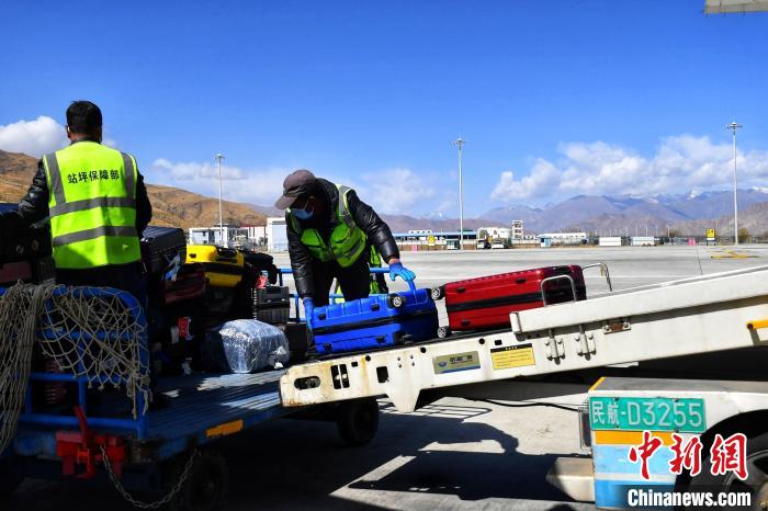 圖為機場工作人員傳送旅客行李箱。　周航 攝