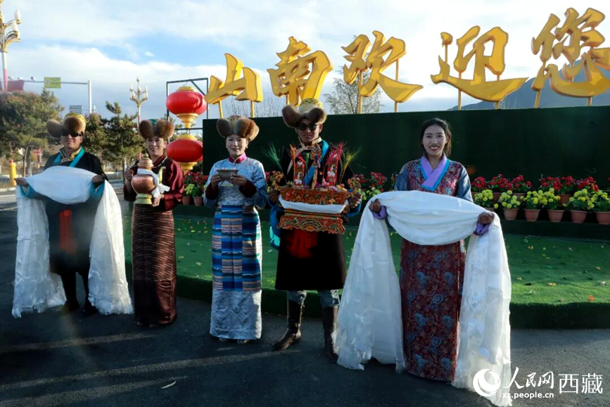 扎西曲登社區(qū)的居民在“山南歡迎您”標(biāo)志前，手持潔白哈達(dá)和切瑪，列隊(duì)迎接來自區(qū)內(nèi)外的游客，用最隆重的禮儀開啟一場沉浸式藏歷新年民俗體驗(yàn)之旅。人民網(wǎng)記者 吳雨仁攝