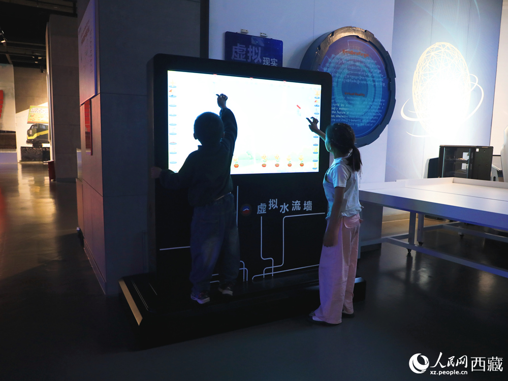 在西藏自然科學博物館科技館的互動展區，孩子們正全神貫注地體驗“虛擬水流墻”，探索流體力學帶來的視覺奇觀與科學樂趣。人民網記者 次仁羅布攝