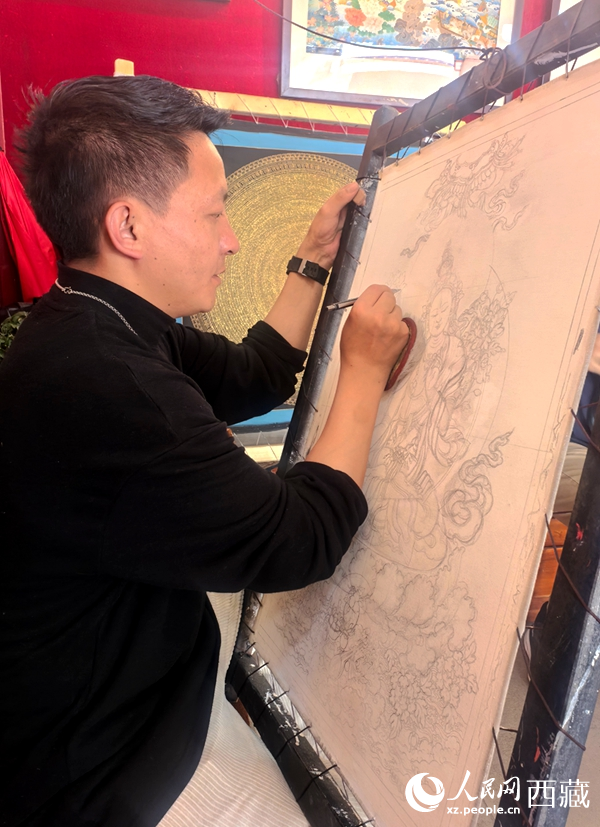 在八廓古城的一家唐卡體驗館內，一位畫師正手持畫筆，在畫布上細細勾勒線條。人民網記者 吳雨仁攝