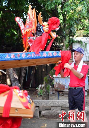 圖為5月29日,長樂江田鎮(zhèn)村民為即將入水的新龍舟系紅布。 張斌 攝