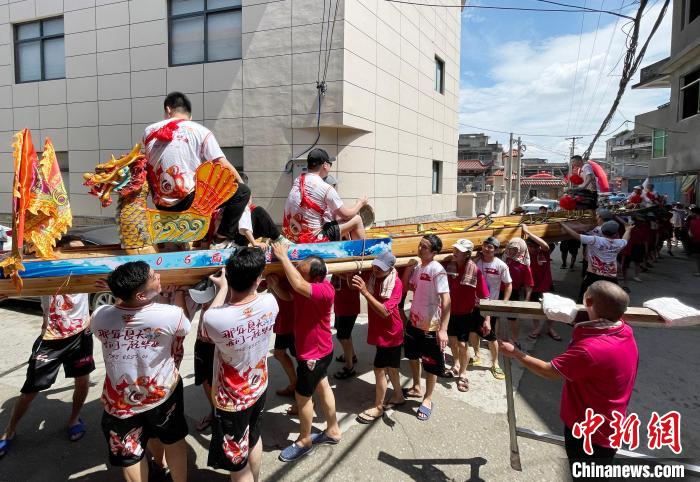 圖為5月29日,長樂江田鎮(zhèn)村民們肩扛著新龍舟舉行入水前游街儀式。 張斌 攝