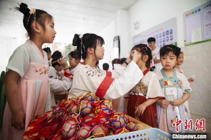 圖為幼兒園的老師們穿上漢服為小朋友們戴上彩蛋，寓意著幸福安康。　董觀生 攝