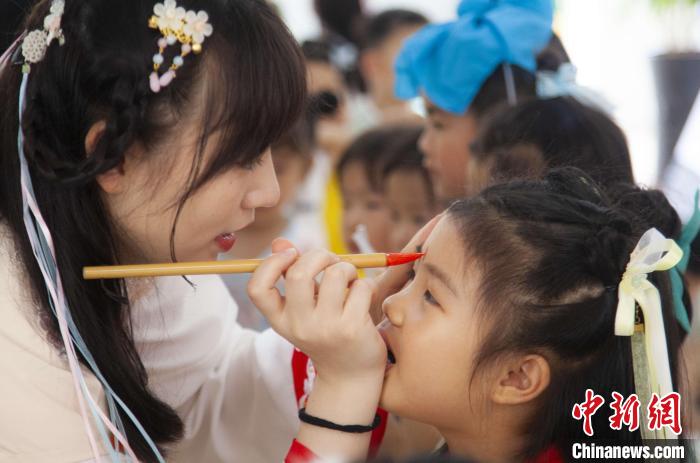 圖為老師在孩子們額頭上點(diǎn)上雄黃，驅(qū)邪辟禍?！《^生 攝